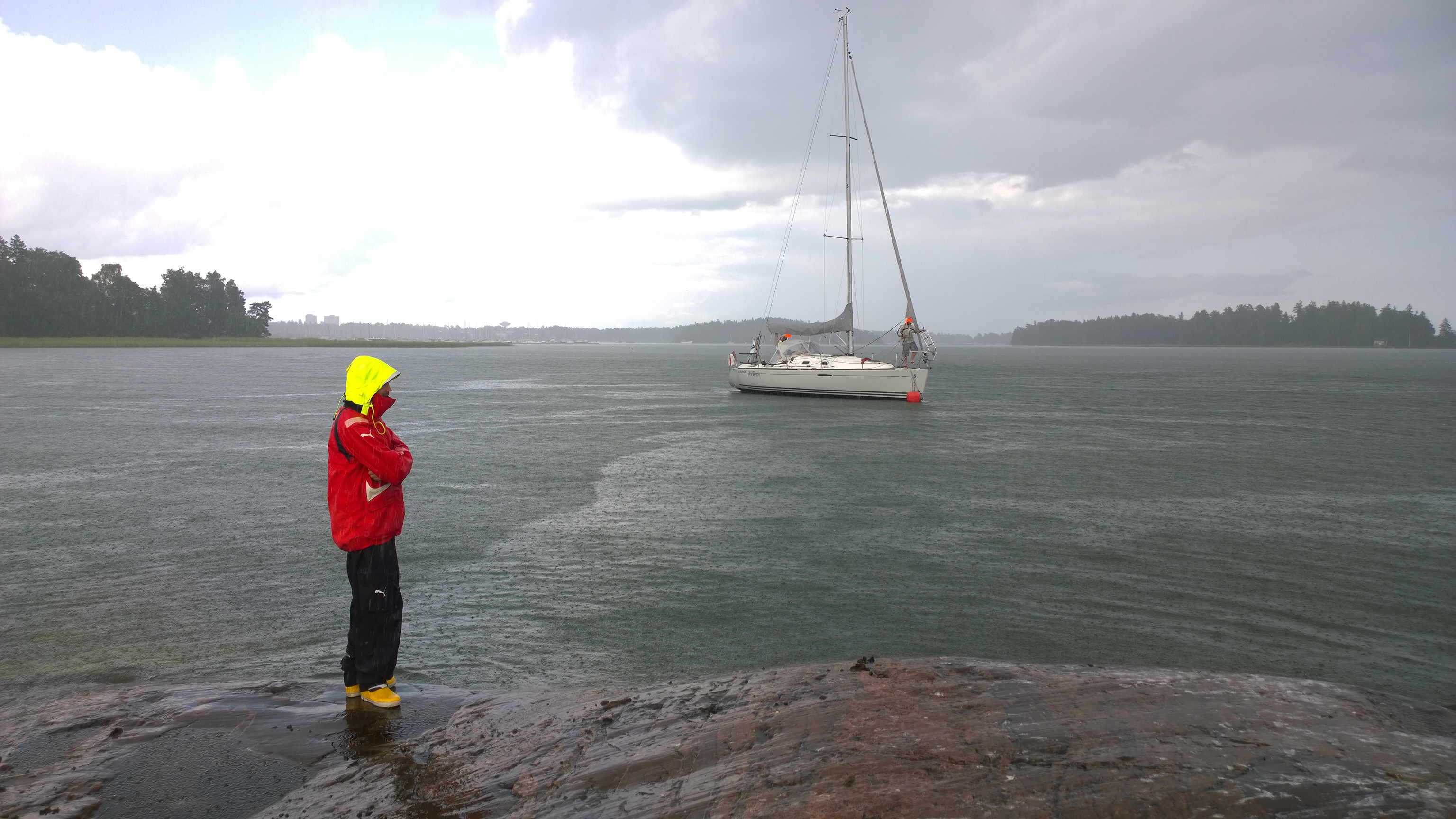 Juuri ennen rantautumista alkoi sataa ihan kunnolla muuten aurinkoisen päivän jälkeen. Olin lähettänyt Jaakon vastaanottamaan venettä jo aikapäiviä sitten, koska itse leivoin korvapuusteja, enkä "mitenkään pysty jättämään näitä pullia tähän!" Niinpä Jaakko odotti ehkä noin vartin kaatosateessa ja minä pääsin avuksi siinä kohtaa, kun sade jo hiljeni i. Eikös olekin tyytyväisen näköinen mies rannassa?